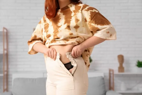 Image of woman trying to do her trousers up after pregnancy weight gain Aberdeen